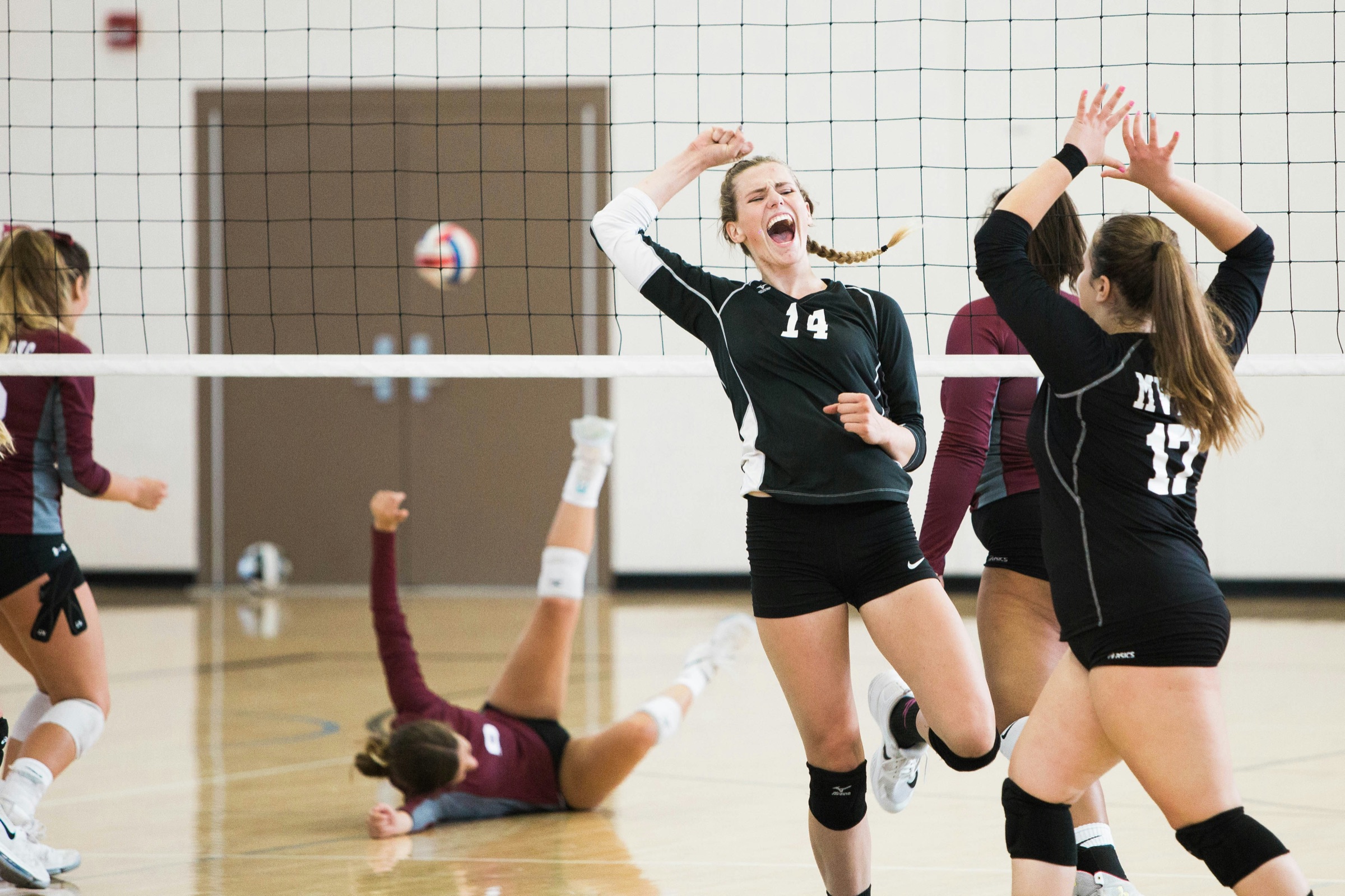 High school girls volleyball team celebrating a point during an indoor match
