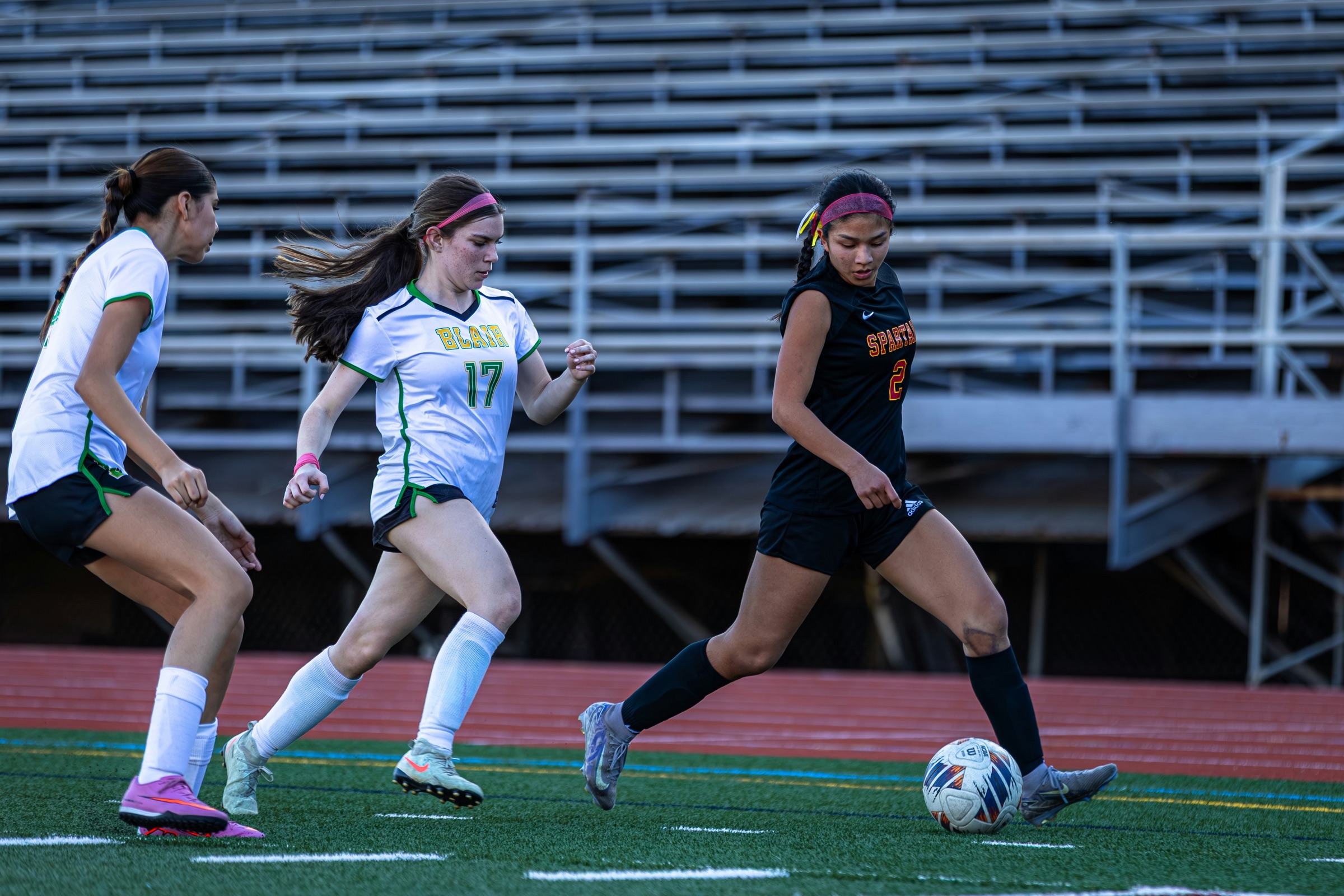 Young women playing soccer on a grass field